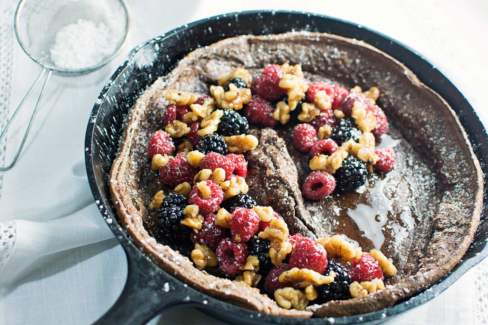 Enjoy a decadent breakfast or dessert with this Chocolate Dutch Baby served with fresh fruit and drizzles of warmed maple syrup and toasted walnuts! Recipe @LittleFiggyFood