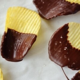 Chocolate-dipped potato chips on parchment paper.