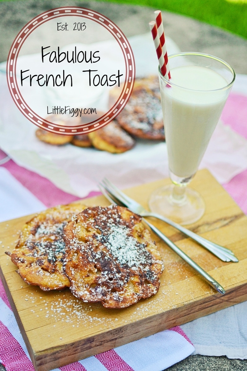 A wooden board holds three slices of French Toast dusted with powdered sugar, alongside a fork, knife, and a glass of milk with a red-striped straw. A pink cloth and more French Toast appear in the background. Text reads Fabulous French Toast.