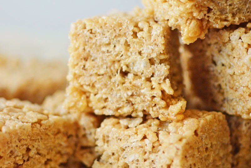 Close-up of stacked Rice Crispy Treats, highlighting their textured, crispy surface and gooey, caramel-colored marshmallow binding.