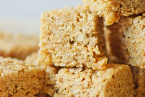 Close-up of stacked Rice Crispy Treats, highlighting their textured, crispy surface and gooey, caramel-colored marshmallow binding.