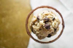 A close-up, top-down view of Double Chocolate Chip Cookie Dough with chocolate chips and white chocolate chunks on a blurred neutral background.