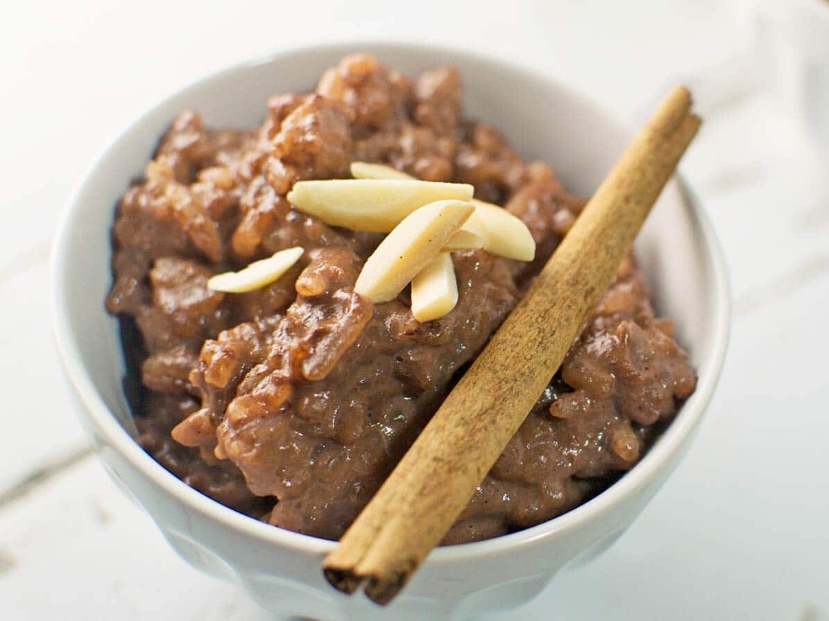 Cinnamon rice pudding topped with almonds in bowl.