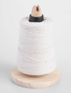 A spool of white twine is wrapped around a wooden holder with a round base. A wooden tip and black section secure the twine at the top. The background is plain white.