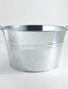 A large, round galvanized metal tub with two wooden handles on either side is placed on a plain white background.