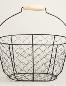 A wire basket with a black metal frame and a wooden handle, photographed against a plain light background. The basket has an open, airy design with a round base and flared sides.