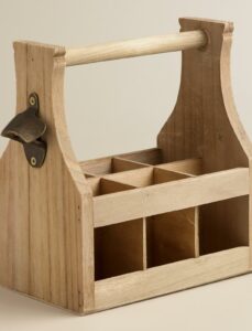 A wooden drink caddy with six compartments, a sturdy handle, and a metal bottle opener attached to one side, placed on a neutral background.