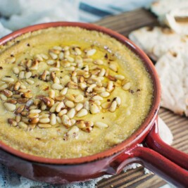 Try this Baked Hummus topped off with buttery, toasted pine nuts and served up with some pita bread! It's great for your next get together, or as a snack. Recipe @LittleFiggyFood