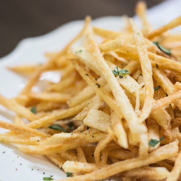 Shoestring French Fries In White Paper Bag On Picnic Table Stock