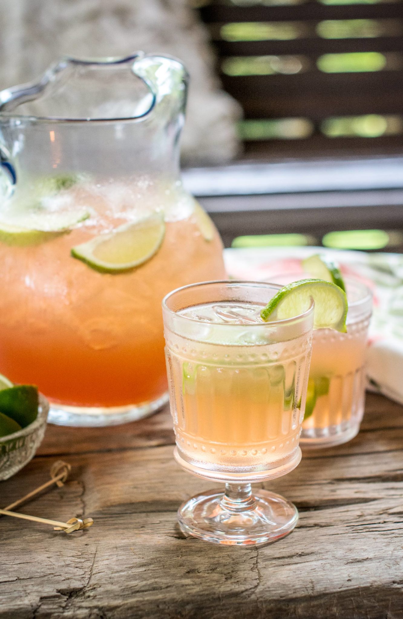 Clear glasses and pitcher filled with Scarlet O'Hara Cocktail punch and garnished with lime wedges