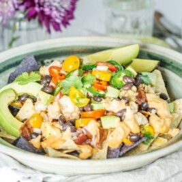 Plate of nachos with avocado and vegetables.