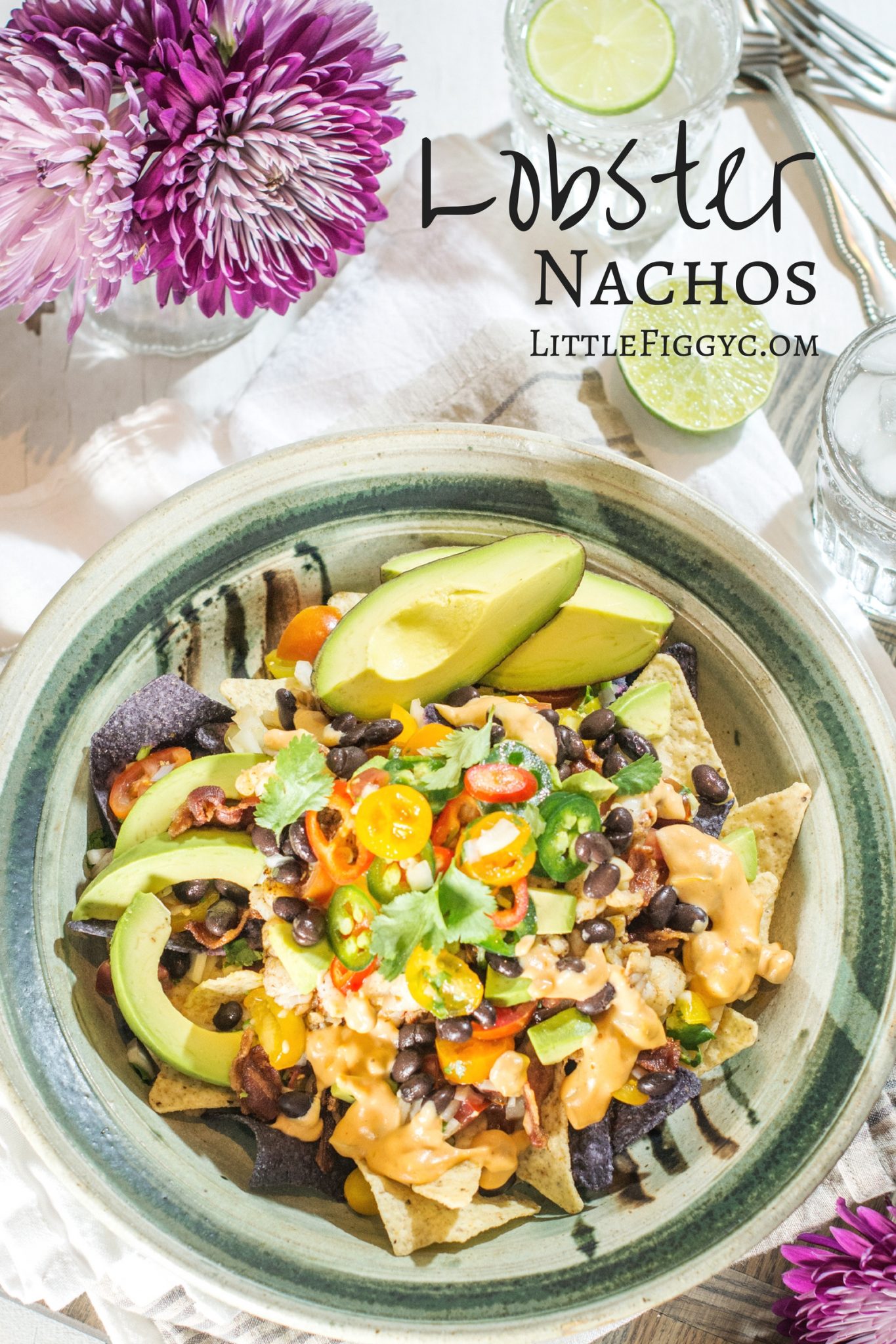 Lobster nachos topped with cheese sauce, black beans and avocado in a green rimmed bowl shot from overhead.