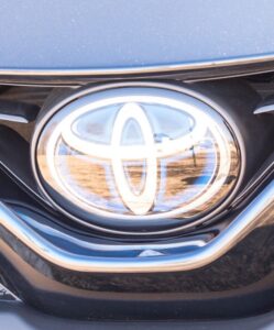 Close-up view of the front grille of a car featuring a shiny silver Toyota emblem in the center, with black detailing and reflections that catch the eye—almost as tempting as a plate of Lobster Nachos.