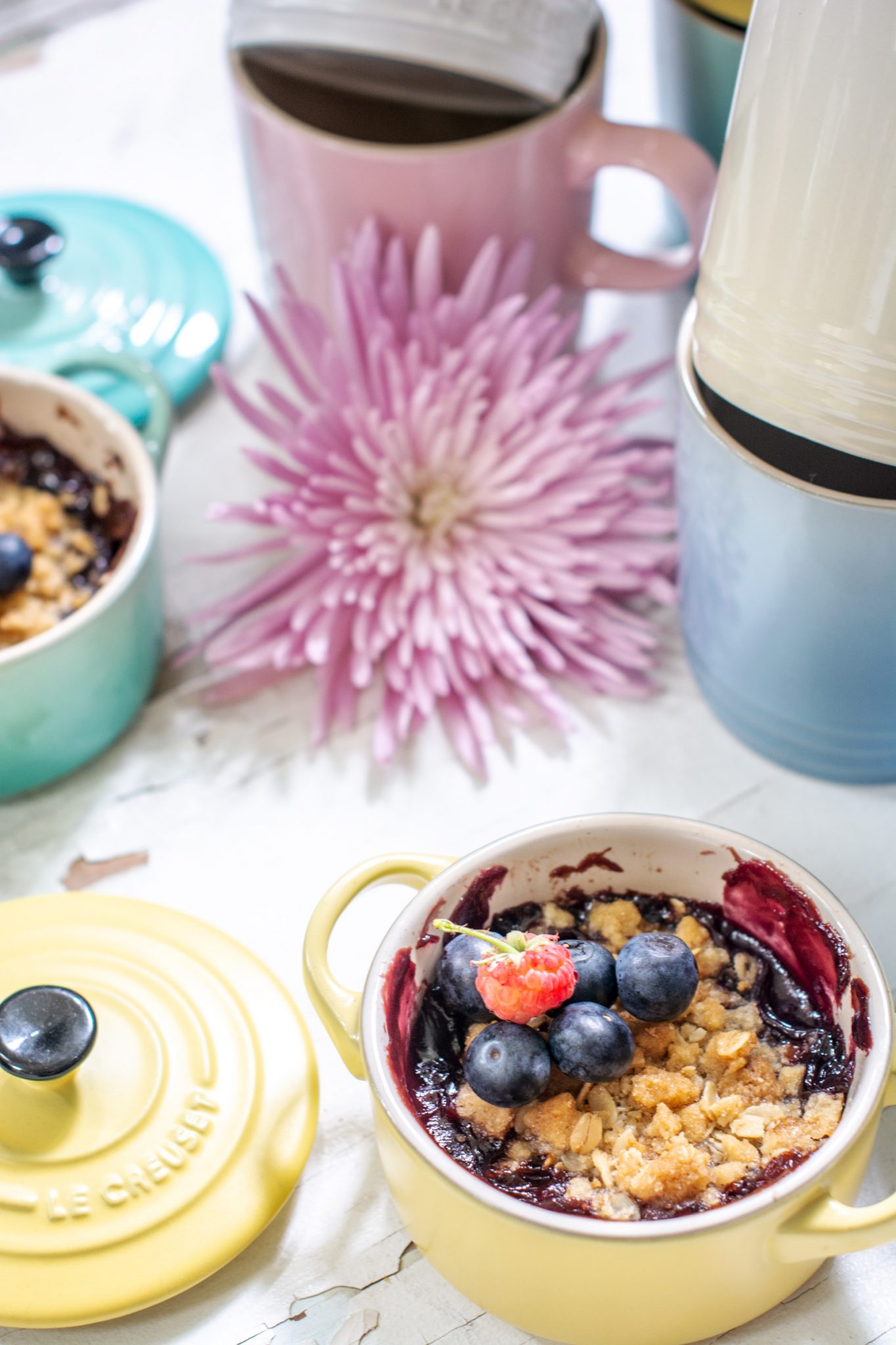 Raspberry and Blueberry crisp recipe in yellow dish with pink flower on white table