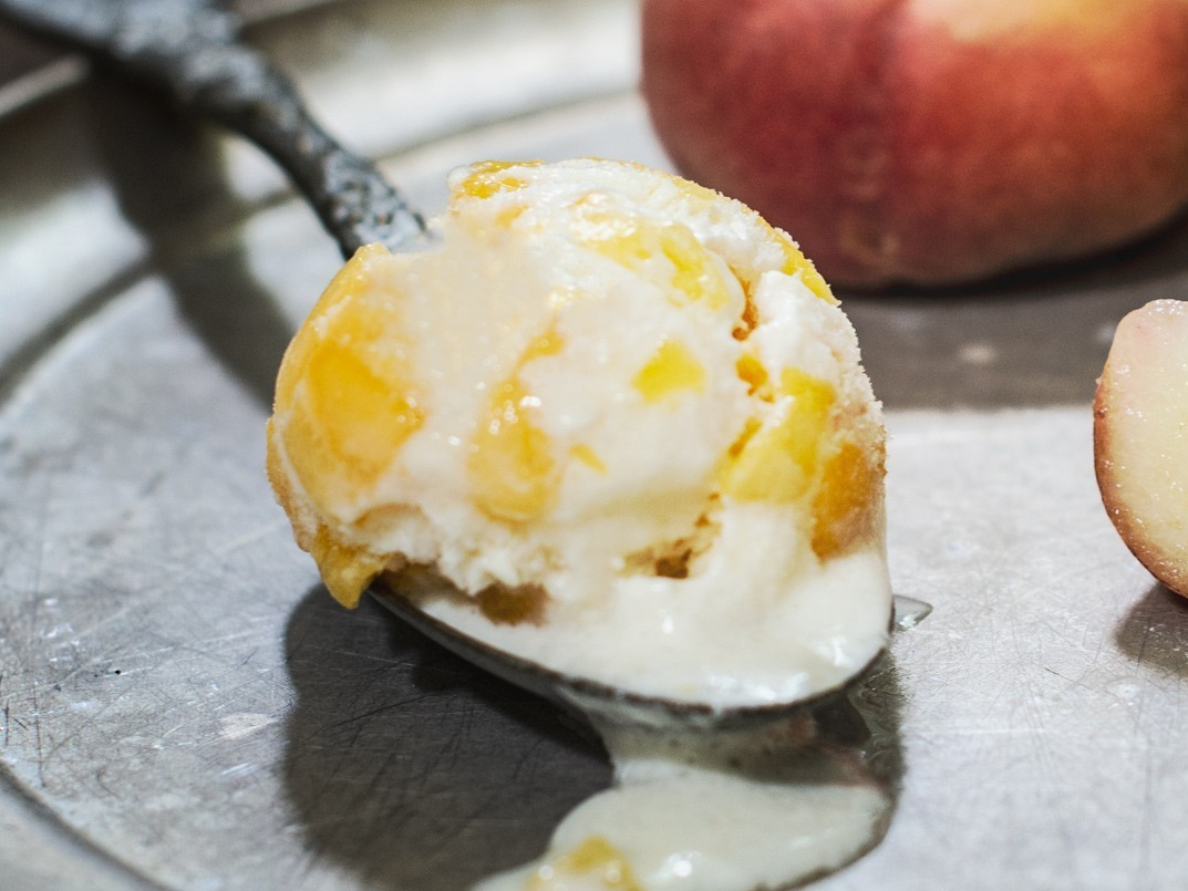 Peach ice cream scoop and fresh peach slices.