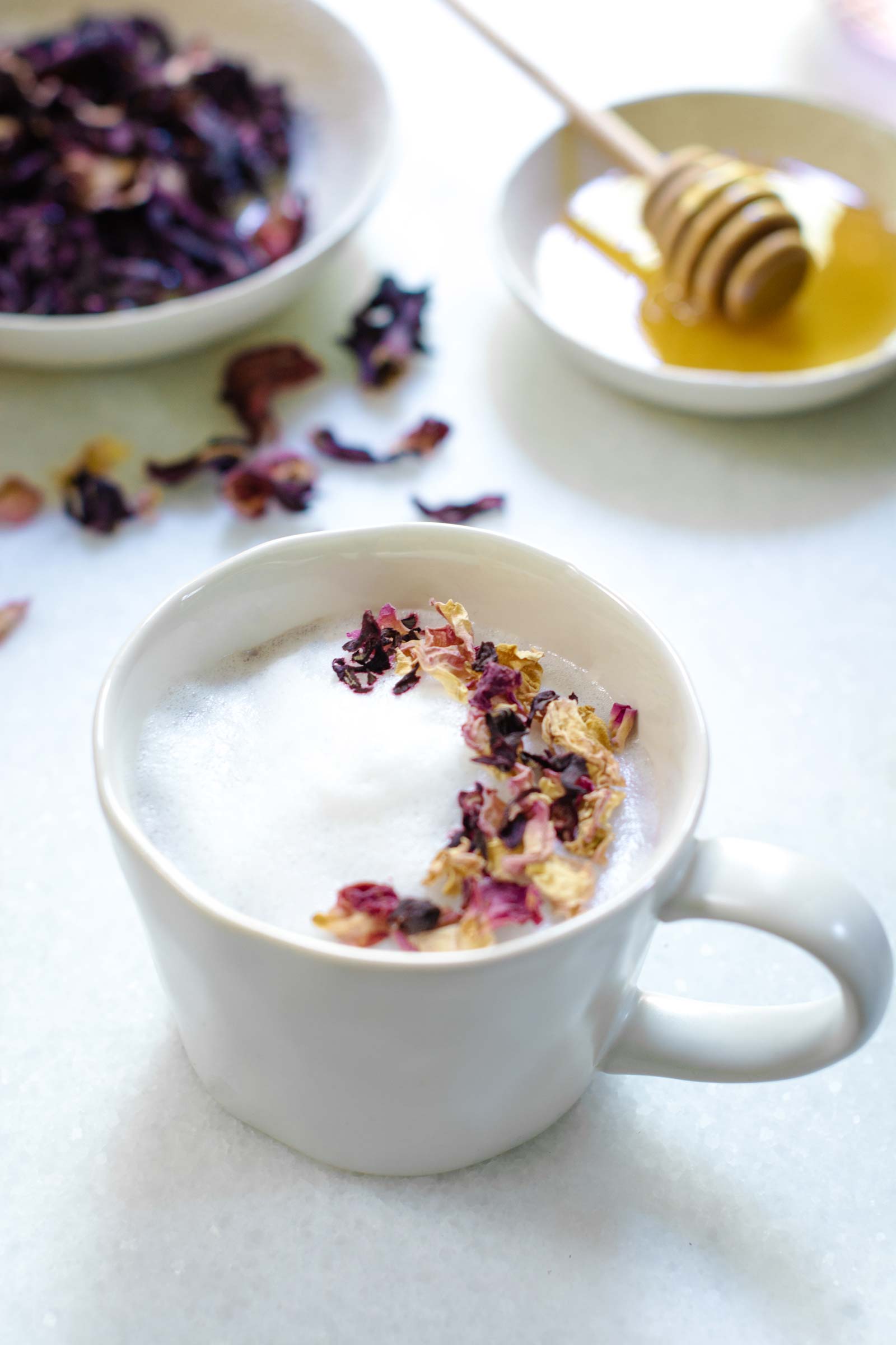 White mug of tea and steamed milk decorated with pink flowers