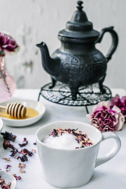 Hibiscus Flower Tea Latte with honey on white table