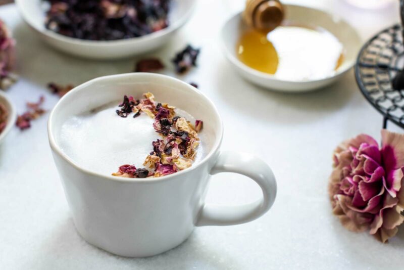 White table with frothy milky tea garnished with dried flowers