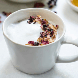 Frothy tea with dried flower petals in mug.