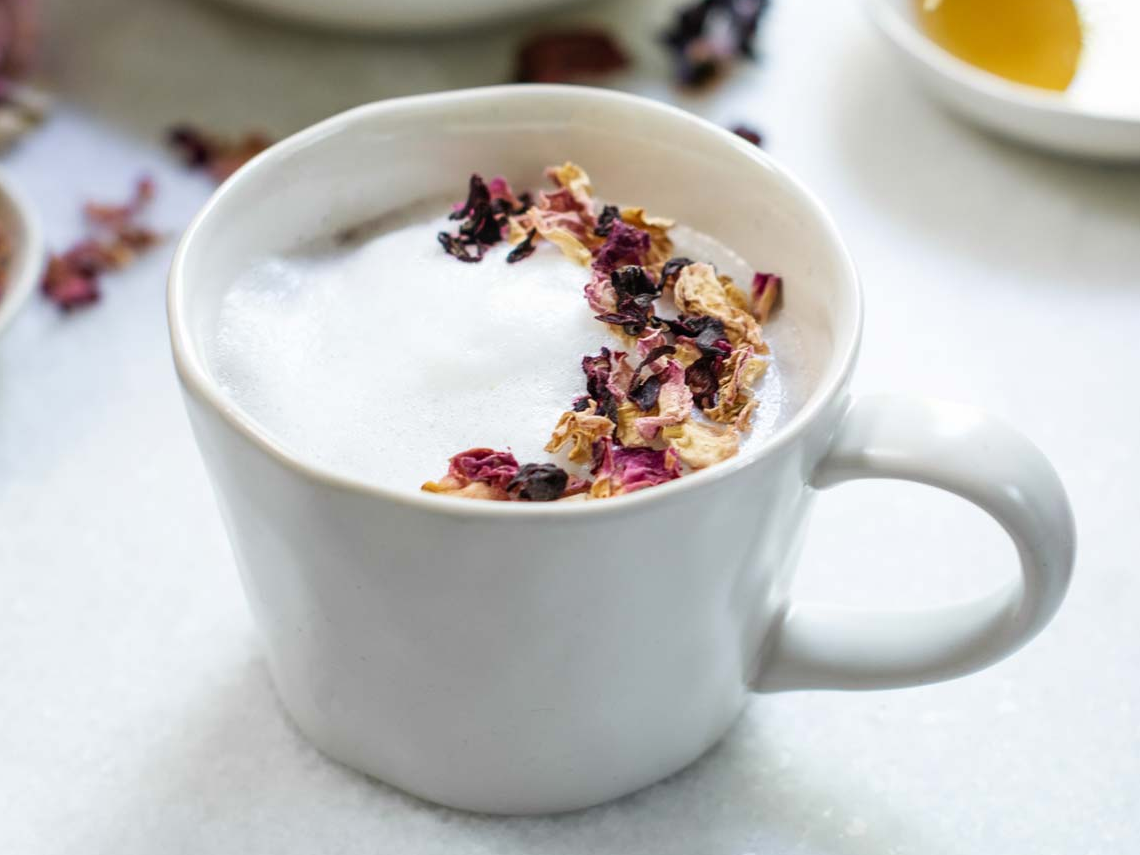 Frothy tea with dried flower petals in mug.