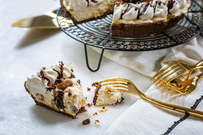 A slice of Edwards Turtle pie with gold forks and pie in background on white table