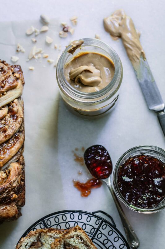 White table with spoon of jelly and knife with peanut butter and open jars