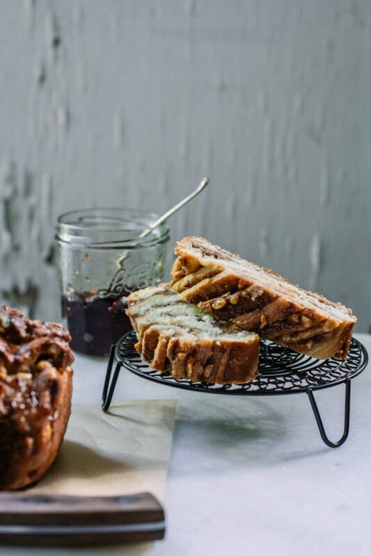 Serving slices of sweet bread with jar of jam on white table