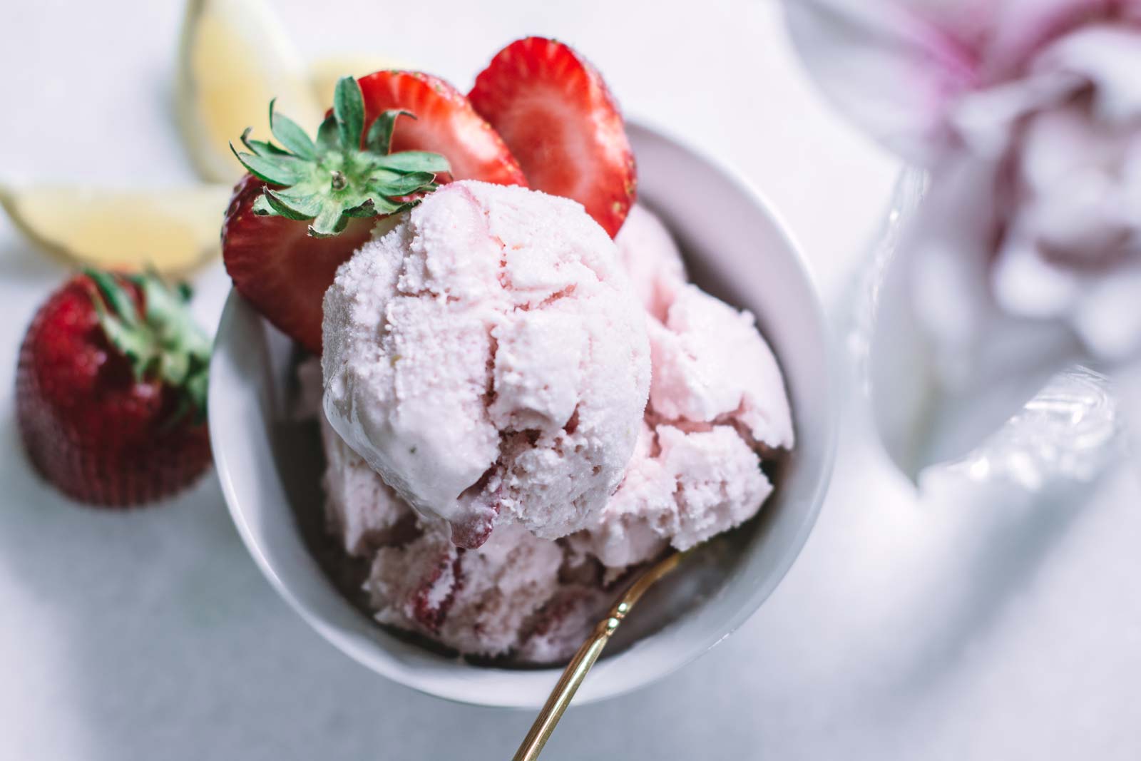 White table with bowl of pink yogurt and fruit