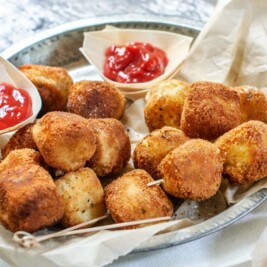Crispy potato croquettes with ketchup on a plate.