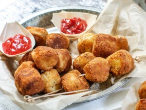 Crispy potato croquettes with ketchup on a plate.