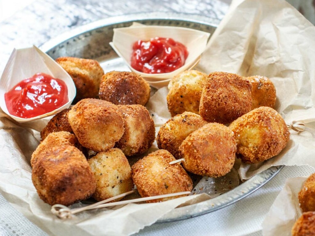 Crispy potato croquettes with ketchup on a plate.