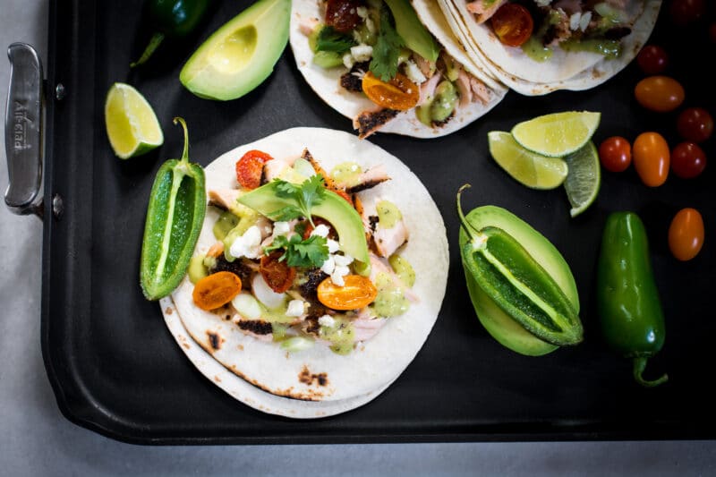 Fish tacos served with avocado, salsa, and jalapenos