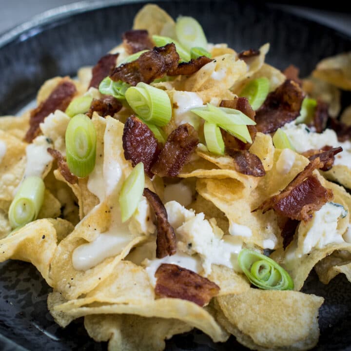 A pile of potato chips, served as an appetizer with a cheesy dipping sauce