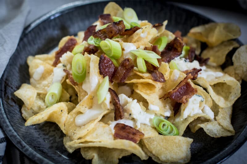 A pile of potato chips, served as an appetizer with a cheesy dipping sauce