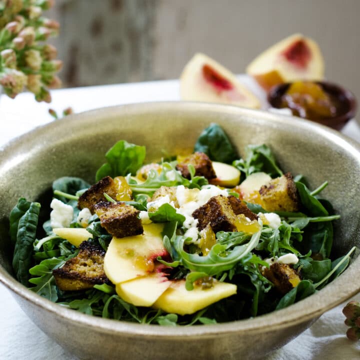 Serving a fresh bowl of farmers salad with fruit and croutons