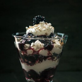 Blackberry parfait with whipped cream in glass.