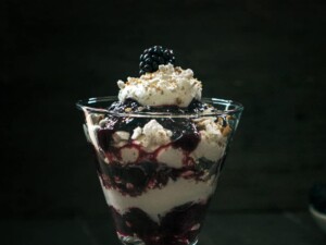 Blackberry parfait with whipped cream in glass.