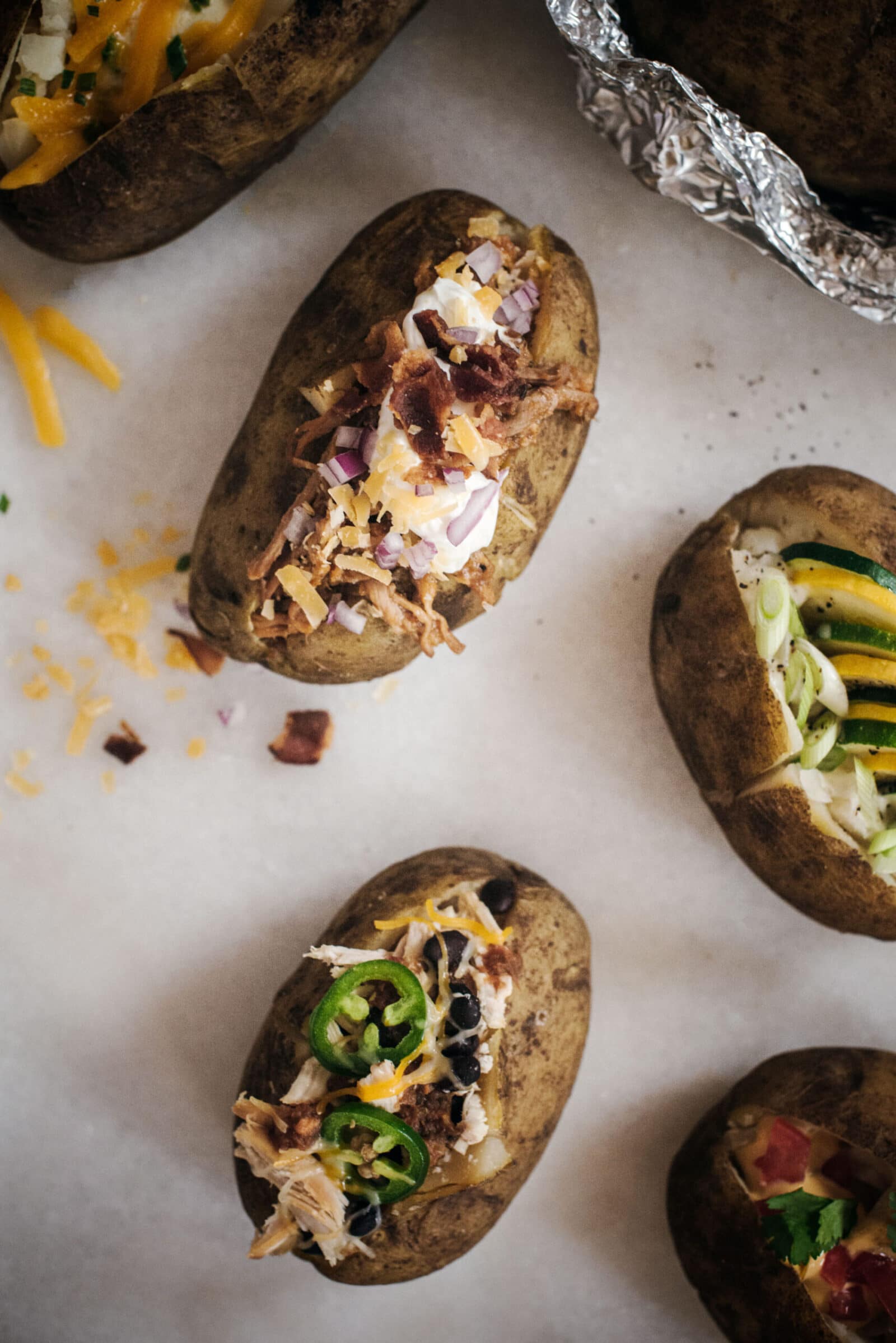 Board of baked potatoes with a variety of toppings