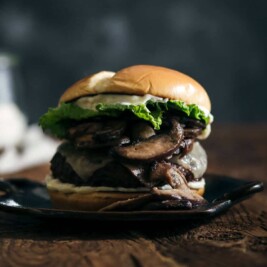 Gourmet burger with mushrooms and lettuce on plate.