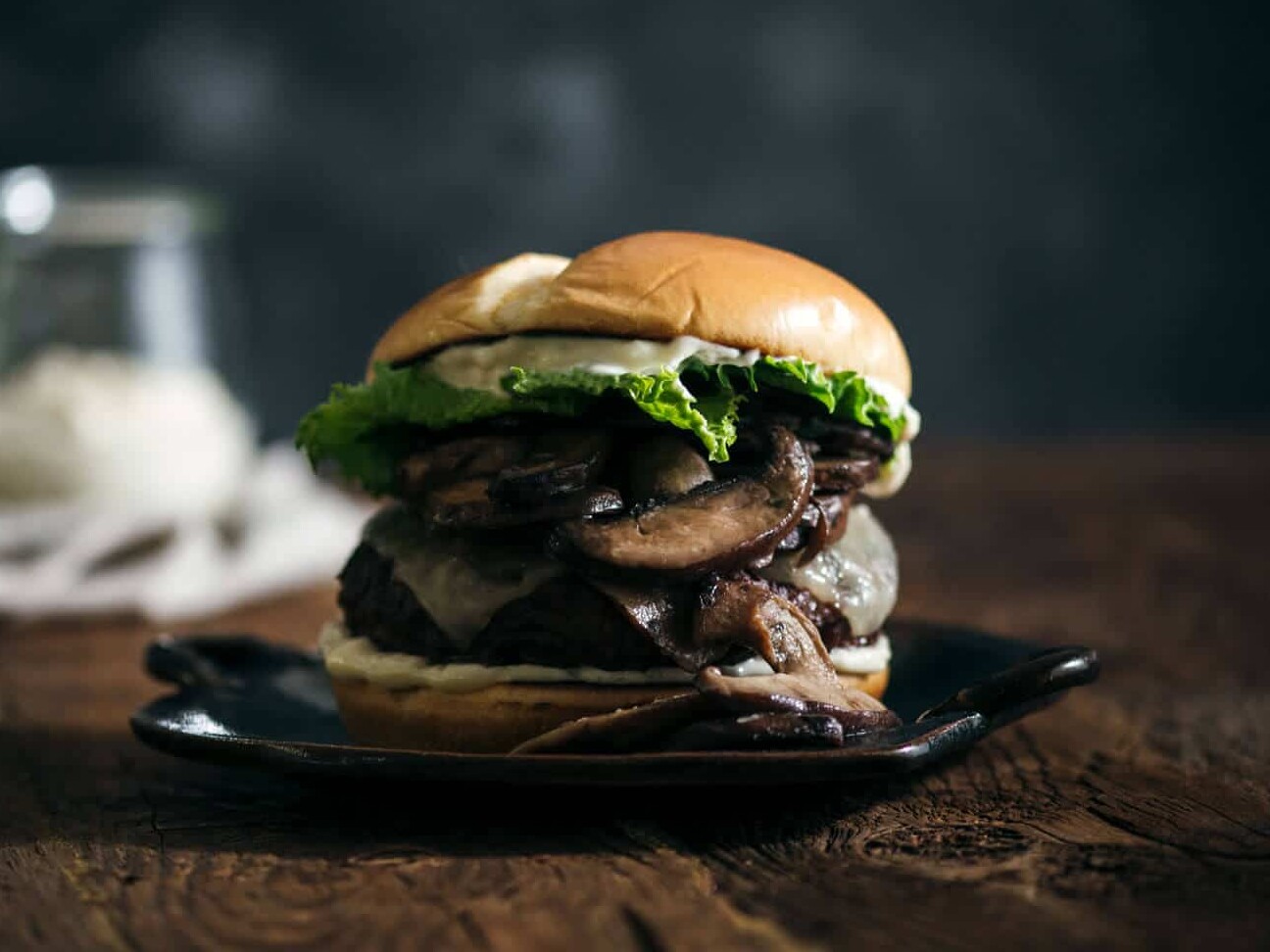 Gourmet burger with mushrooms and lettuce on plate.