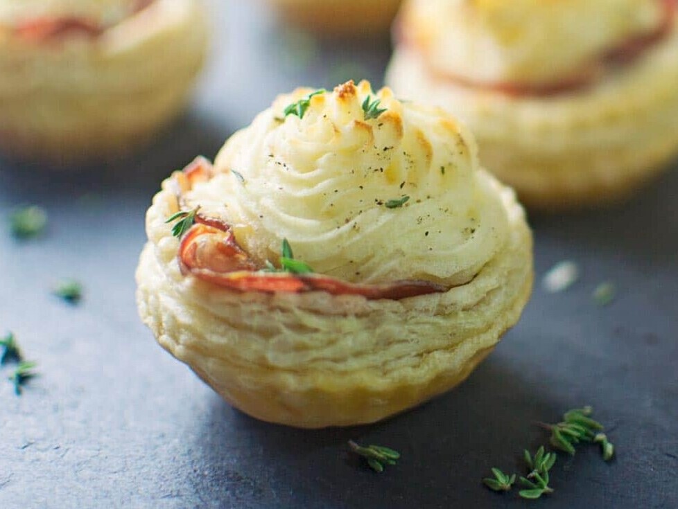 Savory puff pastry appetizers with herbs on slate.