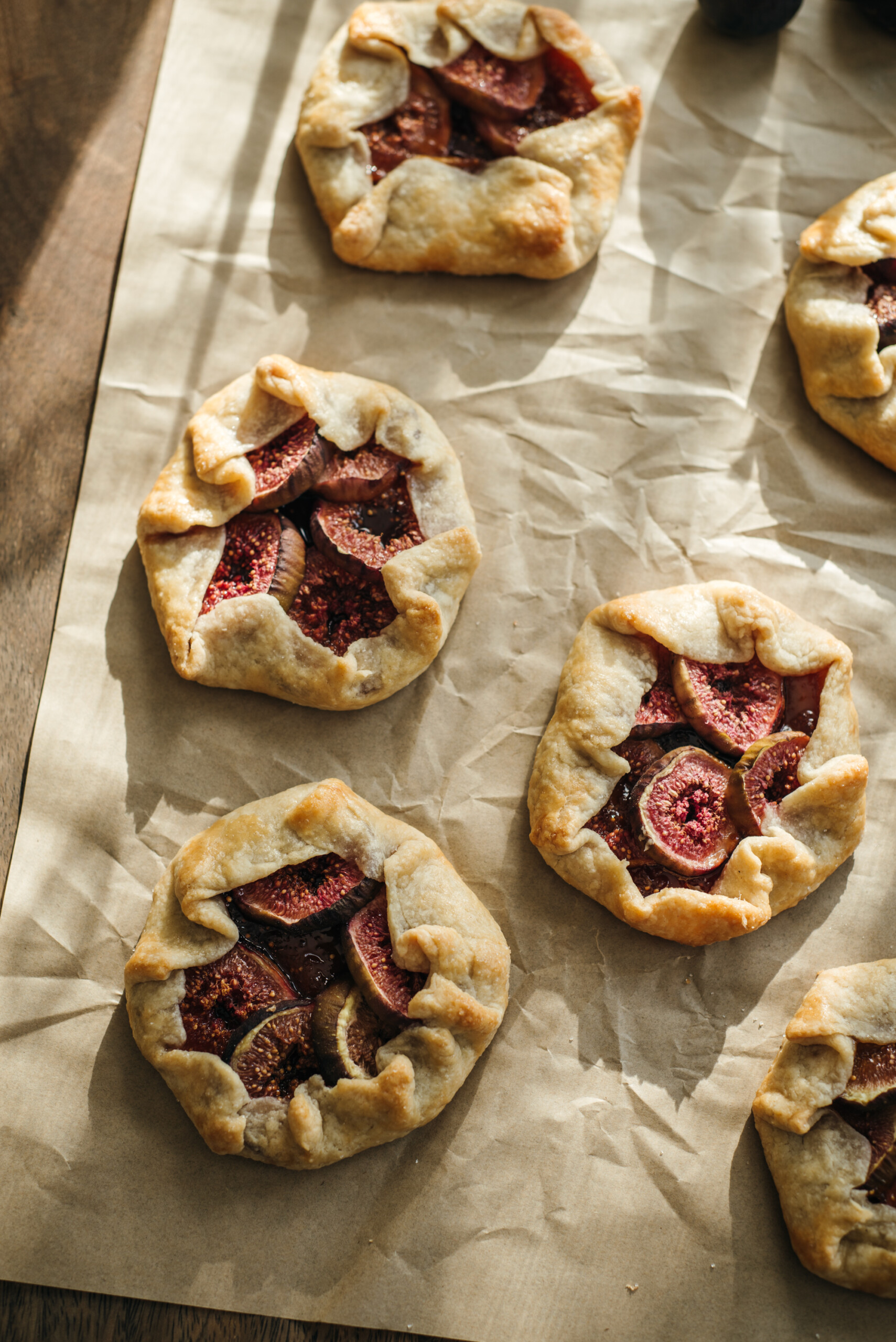 Overhead view of honey-drizzled fig galettes arranged neatly on parchment paper, showcasing their golden crust and rich fig filling.